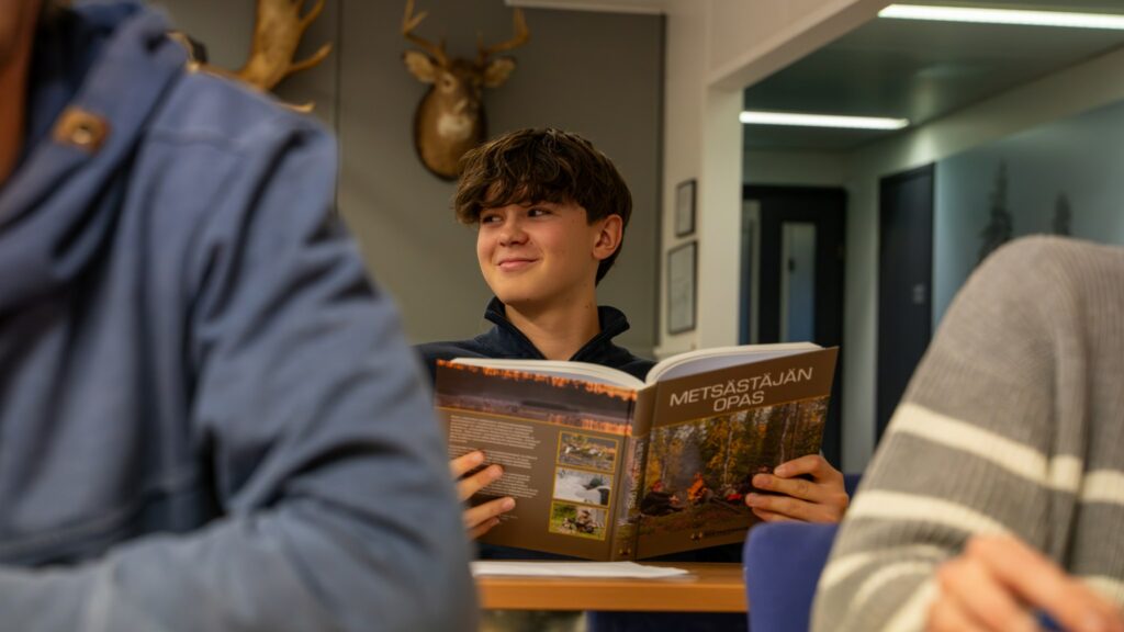 En leende kursdeltagare läser Handbok för jägare.